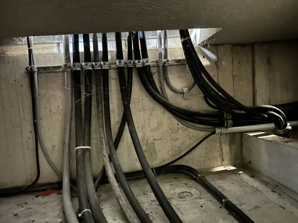 Gebündelte Leitungen, mit Schellen unter der Decke einer Tiefgarage verlegt