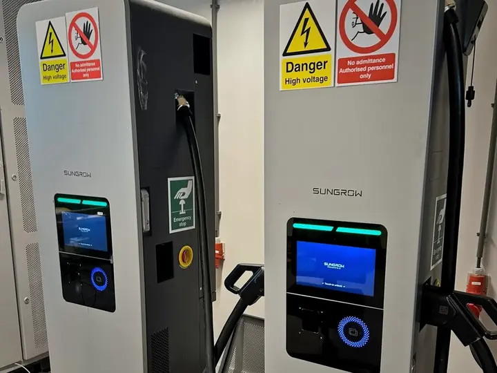 Zwei Sungrow-DC-Ladesäulen mit Display und Ladekabeln im Labor