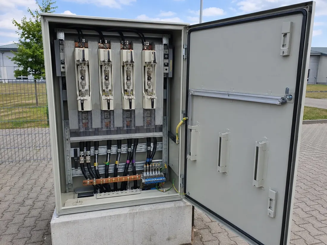 Beispiel aus einem unserer Projekte: geöffneter Anschlussschrank mit NH-Sicherungslasttrennern und Kabelabgängen auf einem Betonsockel